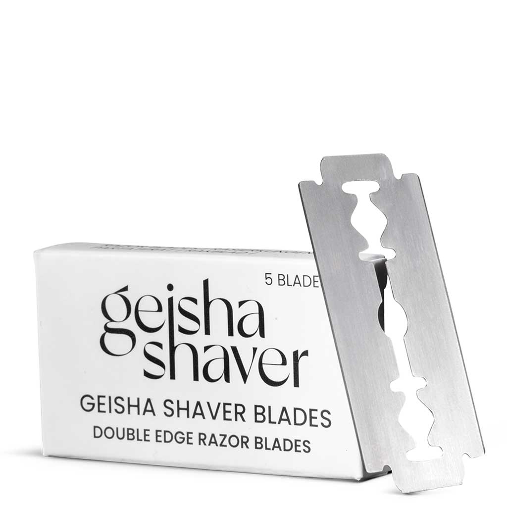 Geisha Shaver Vaihtoterät; suorakulmainen pakkaus mattapintaisena, pääosin valkoinen puna-mustin ja beigein värilohkoin, kylkeen nojaava metallinen kaksiteräinen partaterä; teksti lihavoitua groteskikirjasinta mustalla ja punaisella; terä hopeanvärinen ja heijastava; valkoinen tausta, ei ihmisiä tai käsiä, lähikuva tuotteesta.
