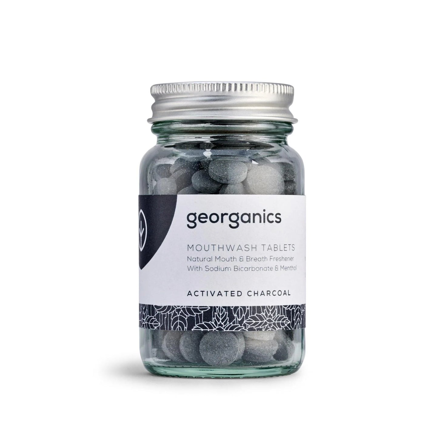 Georganics Suuvesitabletit Aktiivihiili: sylinterimäinen läpinäkyvä lasipurkki hopeisella metallisella kierrekannella, sisältää harmaita tabletteja; valkoisessa etiketissä yksinkertaista musta-sinistä groteskikirjasinta, luettelossa mainitaan natriumbikarbonaatti ja aktiivihiili; tuote kuvattu neutraalia taustaa vasten suoralta edestä, ei ihmisiä tai käsiä näkyvissä.
