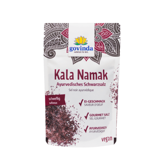 Govinda Kala Namak Mustasuola; ayurvedisen mustasuolan pussi, viininpunainen ja valkoinen väritys, mattapinta, suorakulmainen muoto; pakkauksessa saksan- ja ranskankielistä tuotekuvausta selkeällä groteskikirjasimella; etiketissä merkintä vegaanisuudesta; kuvattu yksivärisellä taustalla, ei ihmisiä tai käsiä näkyvissä.