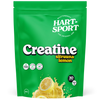 Hart-Sport Creatine Lemon; vihreä uudelleensuljettava pussi Hart-Sport Creatine -jauhetta sitruunanmaussa; etusivulla eloisia sitruunakuvia, tuotehyötyjä kuten vahvuuden ja kestävyyden parantamista sekä annostietoja suomeksi ja englanniksi; mattapinta lihavoidulla valkoisella ja keltaisella groteskitekstillä kirkkaan vihreää taustaa vasten; pussi pystyssä; ei ihmisiä tai käsiä; kuva tasaisella valkoisella taustalla.