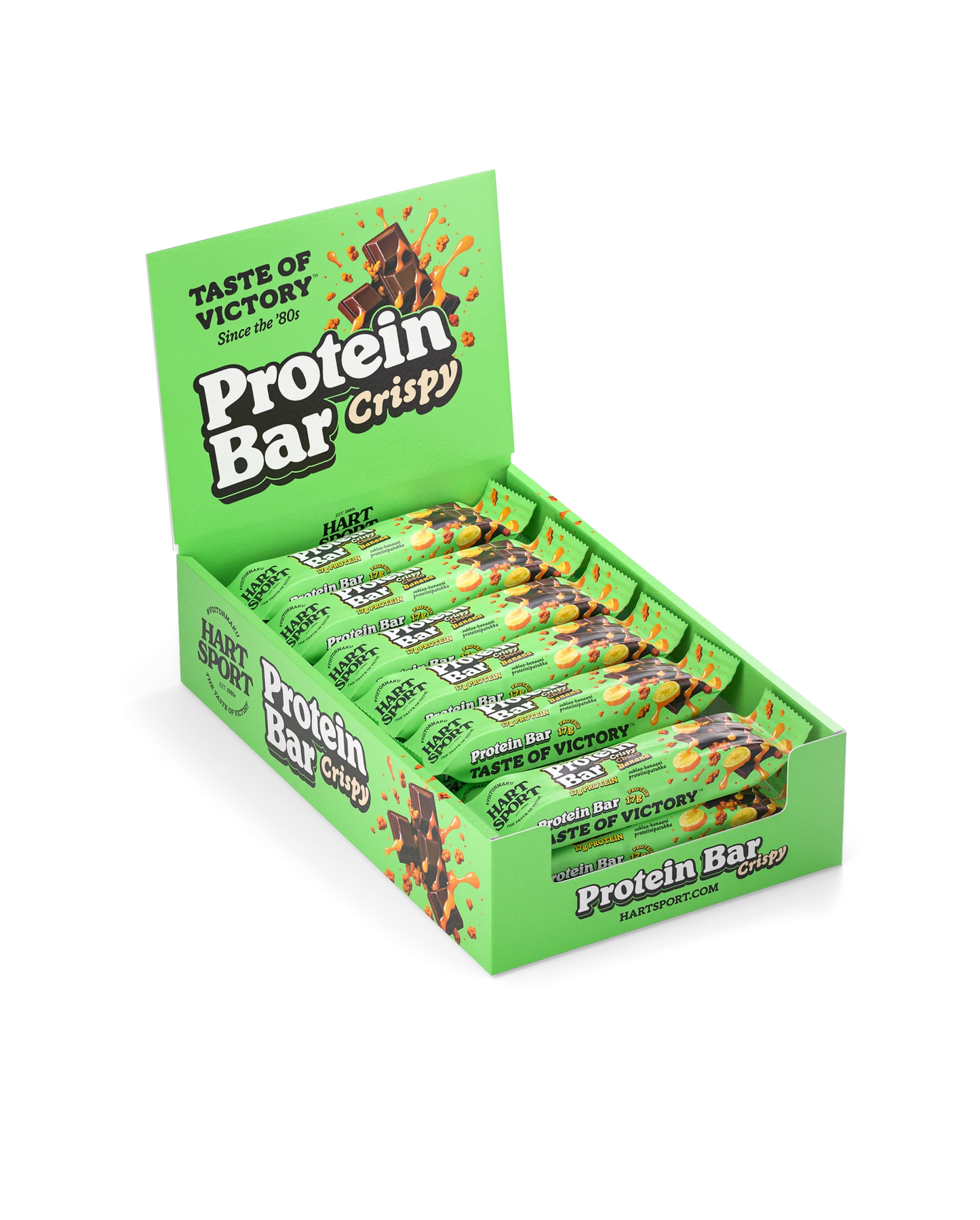 Hart-Sport Protein Bar Crispy Choco Banana; vihreä esittelylaatikko, jossa lukee Protein Bar Crispy, sisältää useita yksittäin käärittyjä patukoita; laatikko on kiiltävää pahvia, siinä kuvia suklaapaloista ja viljanjyvistä; pakkaus on suorakulmainen, aukossa näkyy patukoiden yläosat; lihava valkoinen ja kultainen groteskiteksti sisältää tekstin ”Taste of Victory Since the 80s”; ei ihmisiä tai käsiä näkyvissä; tausta neutraali, tuote kuvattu etuviistosta.
