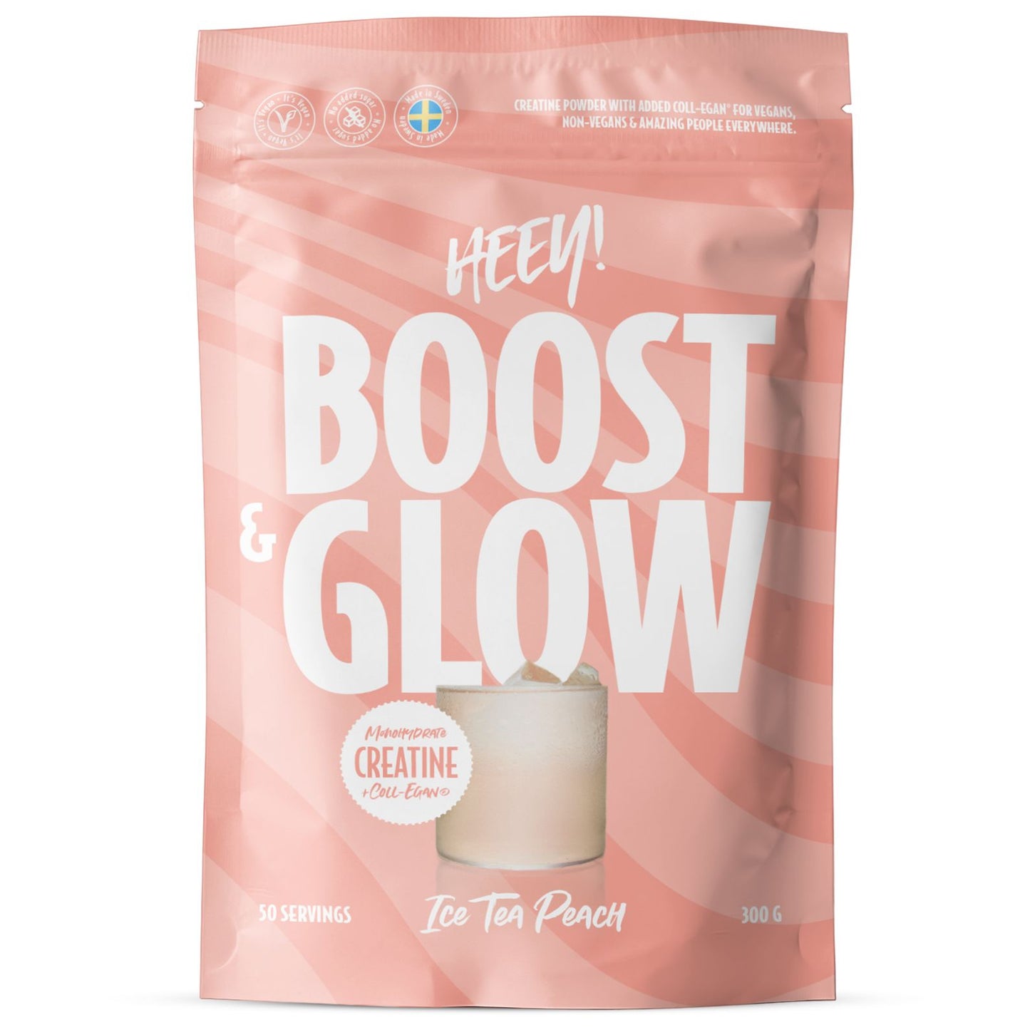 Heey! Boost & Glow Creatine + Coll-egan®, Ice Tea Peach; vaaleanpunainen, mattapintainen pystypussi, jossa lukee BOOOST & GLOW, painettuna persikanvärisiä pyörrekuvioita; pakkauksessa kuva lasista persikkajäätee; valkoisessa groteskitekstissä luetellaan kreatiini ja kauraekstrakti sekä sopivuus sekä vegaaneille että ei-vegaaneille; ei ihmisiä tai käsiä näkyvissä; studiotausta vaalea ja yksivärinen.