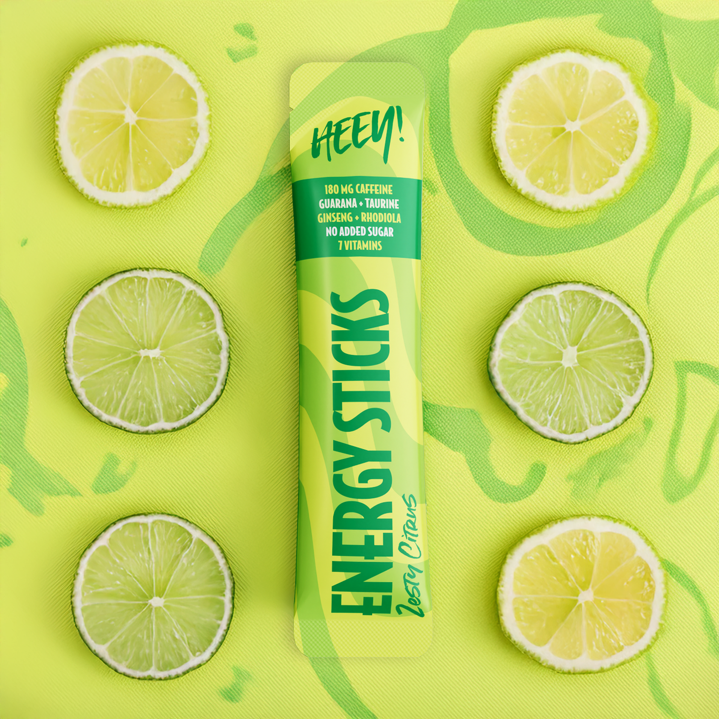Heey! Energy Sticks Caffeine + Guarana, maku Zesty Citrus; pussi nimellä Energy Sticks Berry Citrus lepää neonkeltaisella alustalla, ympärillä kuusi lime- ja sitruunaviipaletta ruudukkomaisesti aseteltuna; pussi kiiltäväpintainen ja suorakaiteen muotoinen, luettava teksti korostaa kofeiinia, vitamiineja ja energiaa lisääviä ainesosia; etiketti lihavoiduin groteskikirjaimin; ei ihmisiä tai toimintaa kuvassa.