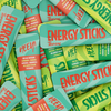 Heey! Energy Sticks Caffeine + Guarana, maku Zesty Citrus; kasa suorakaiteen muotoisia mattapintaisia pusseja vihreän ja turkoosin sävyisenä, tekstillä ENERGY STICKS Tropical ja HEY!, limittäin eri suuntiin; ainesosa- ja kofeiinipitoisuustiedot painettu selkeästi etuosaan groteskifontilla; ei ihmisiä tai käsiä; alusta pussien alla ei näkyvissä.