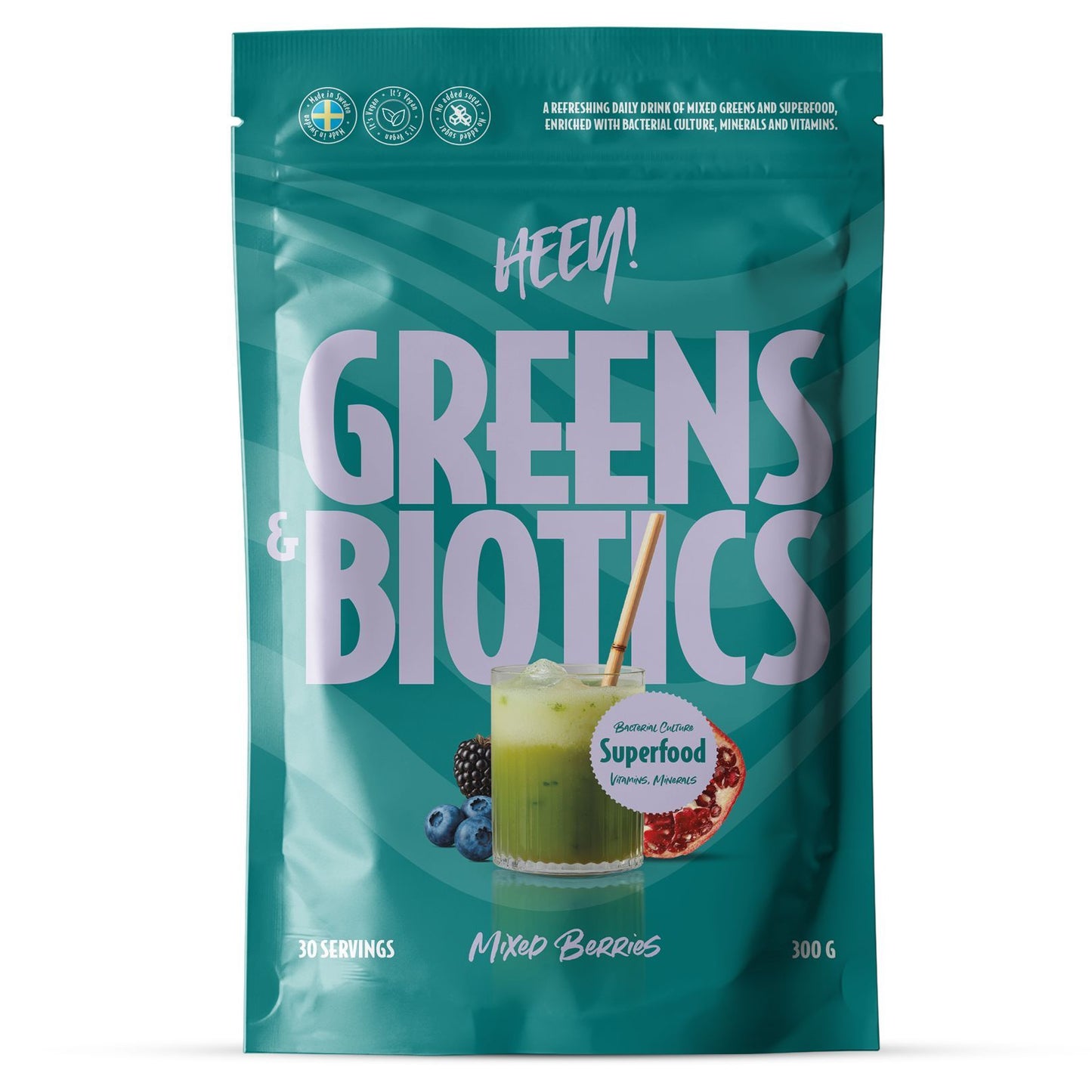 Heey! Greens & Biotics Superfood Mixed Berries: turkoosi mattapintainen pussi pystyasennossa, lihavoitu valkoinen ja marjansävyinen groteskikirjasin; etiketissä kuva lasista vihreää mehua bambupillillä sekä sekoitettuja marjoja; teksti sisältää "HEY! GREENS & BIOTICS Mixed Berries", 30 annosta, 300 g, superfood-ainesosia ja suolistoterveyshyötyjä; neutraali tausta, lähikuva tuotteesta.