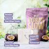 Heey! Hydrate & Glow Electrolytes + Coll-egan® Passionfruit; lasillinen vaaleaa juomaa aseteltuna passionhedelmien ja violetin Hydrate & Glow -pussin väliin; pussi kiiltäväpintainen valkoisin groteskitekstein; näkyvissä olevissa etiketeissä ainesosanimet elektrolyytit, magnesium, vegaaninen kollageeni, koentsyymi Q10, E-vitamiini ja hyaluronihappo; ei ihmisiä tai käsiä; neutraali ja huomaamaton tausta, suoraan edestä kuvattu tuotekuva.