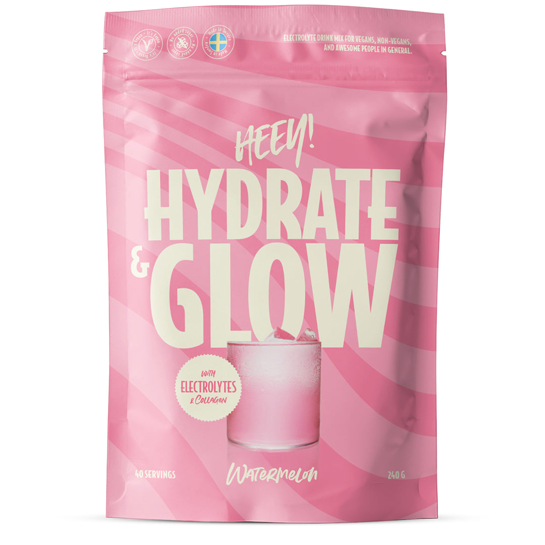 Heey! Hydrate & Glow Electrolytes + Coll-egan® Watermelon; vaaleanpunainen pussi, jossa lukee HYDRATE & GLOW, kuvassa lasi vaaleanpunaista juomaa, maku vesimeloni, sisältää elektrolyyttejä ja kollageenipeptidejä; joustava pussi on mattapintainen, valkoista groteskitekstiä; etiketissä ilmoitetaan 40 annosta ja 240 g; molemmat esineet vaalealla, tasaisella alustalla, ei ihmisiä tai muuta rekvisiittaa kuvassa.