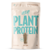 Heey! Plant Protein Iced Latte; beige 500 g:n pussi, jossa lukee HEEY! PLANT PROTEIN suurin sinivihrein kirjaimin, kuvituksena kylmä latte kupissa pillin kera etupuolella; pussin pinta on mattapintainen, muoto suorakulmainen pyöristetyin reunoin; pakkauksen teksti mainitsee vegaaniset ainesosat ja korkean proteiinipitoisuuden; ei ihmisiä tai käsiä näkyvissä, kuva on pelkkä tuotekuva neutraalia taustaa vasten.
