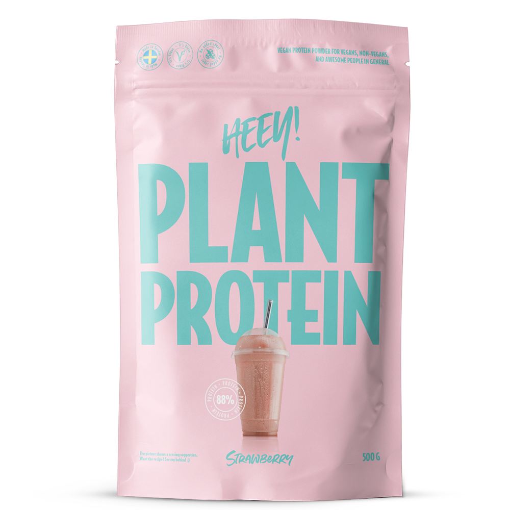 Heey! Plant Protein, maku Strawberry; vaaleanpunainen mattapintainen suorakaiteen muotoinen pussi tekstillä HEEY! PLANT PROTEIN isoin turkoosein kirjaimin, kuvana mansikkasmoothie; etuetiketissä 88 % proteiinipitoisuus, maku mansikka ja nettopaino 500 g; ei ihmisiä tai käsiä; yksinkertainen studiotausta.