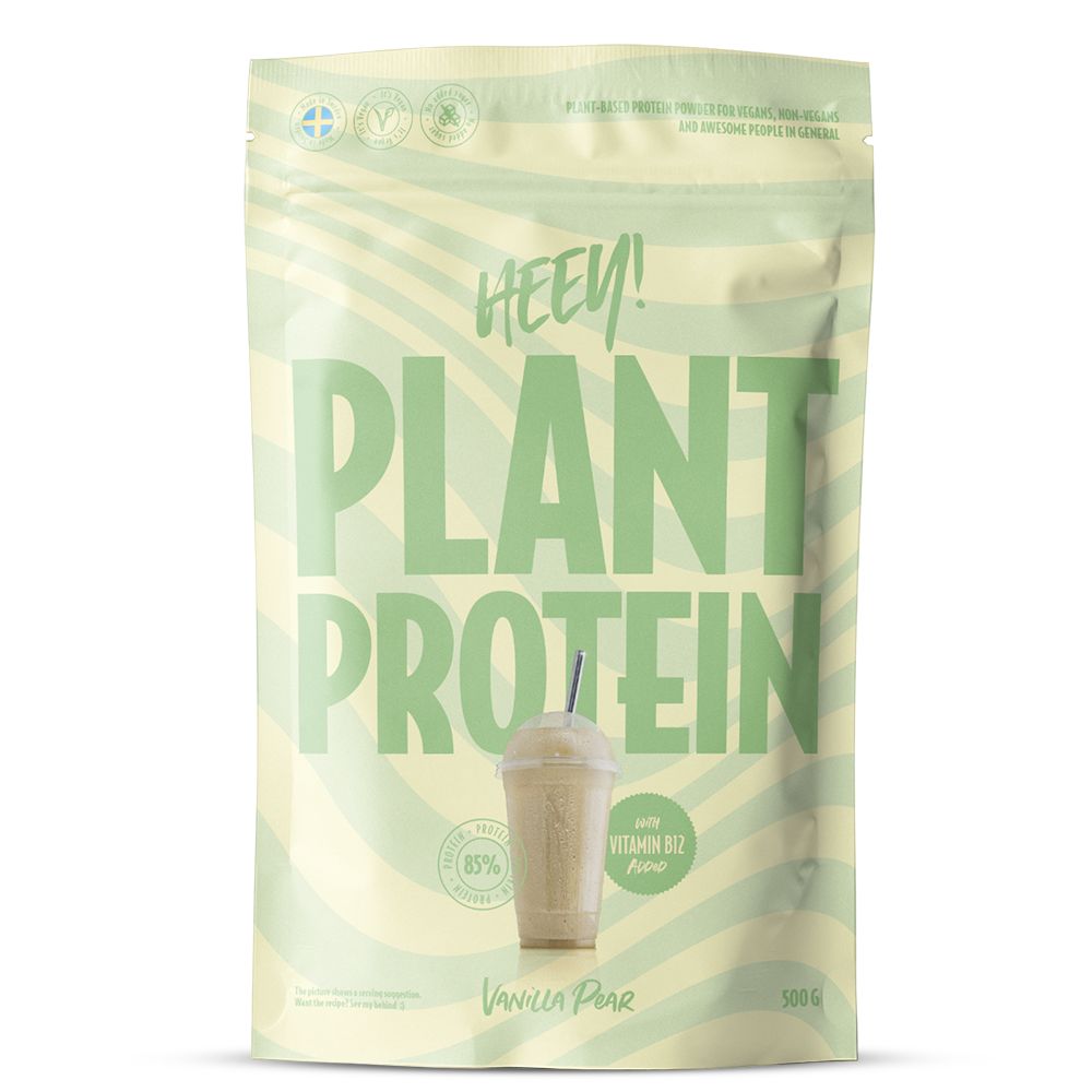 Heey! Plant Protein, maku Vanilla-Pear; vaaleanvihreä pussi tekstillä HEEY! PLANT PROTEIN, kuva vanilja-päärynäshakesta pillin kera; mattapintainen joustava materiaali, suorakaiteen muotoinen pohja, lämpösaumatut reunat; lihavoitu groteskityypografia valkoisena ja mustana; etuteksti mainitsee 85 % kasviproteiinia, B12-vitamiinia ja 500 g; ei ihmisiä tai käsiä; vaalea tausta, tuote pystyssä suoraviivaisessa studiokuvassa.