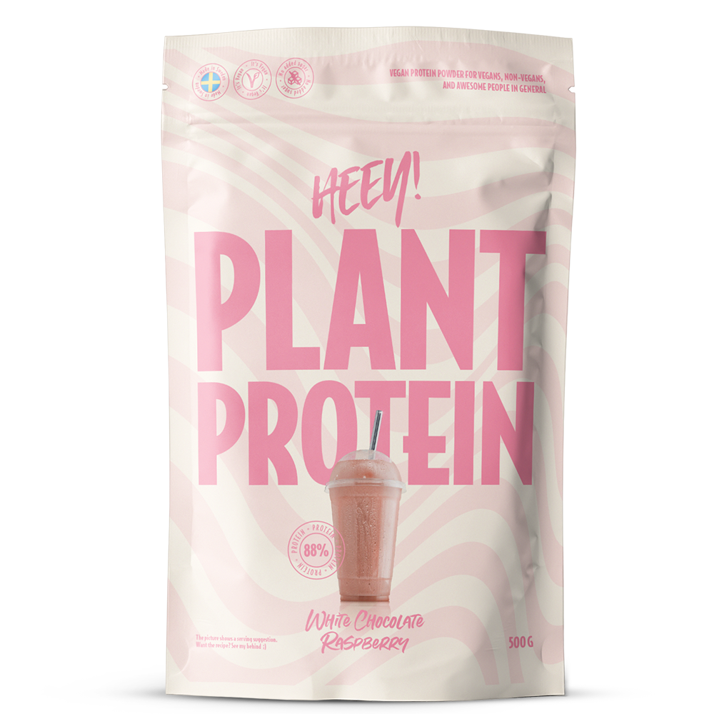 A pink and white pouch labeled HEEY! PLANT PROTEIN with an image of a pink smoothie and text White Chocolate Raspberry. The 500g package features nutrition icons at the top, highlighting its plant protein content. The pouch is rectangular with a matte finish, zip-seal visible at the top edge. Typography is bold sans-serif in white and dark pink. No people or other objects are present; background is plain white, shot shows only the front of the pouch centered in frame.