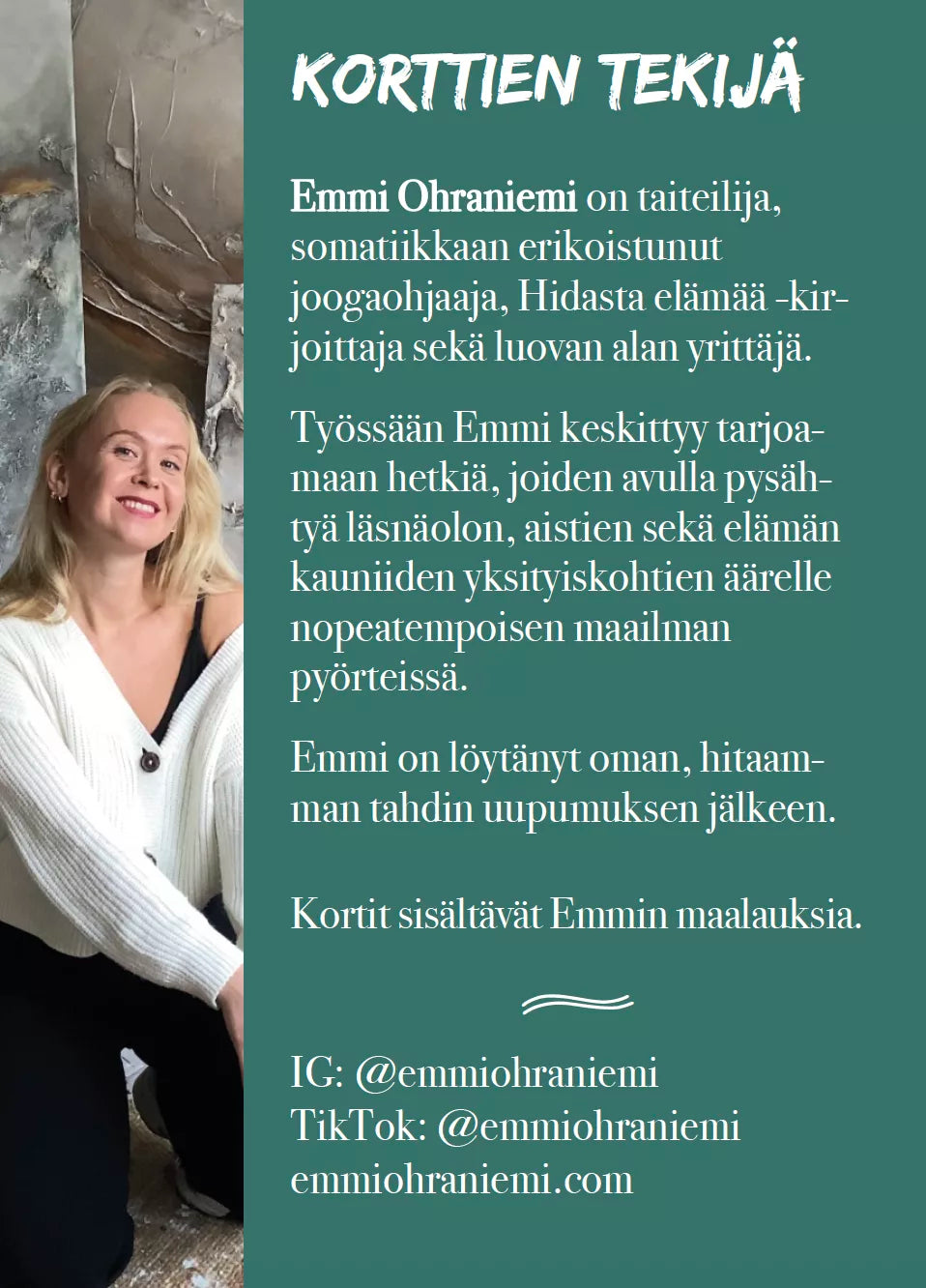 Hidasta Elämää Hitaammassa Tahdissa Rauhoittumiskortit; vaaleatukkainen nainen valkoisessa huppariessa ja mustissa housuissa hymyilee istuen jalat ristissä maalatun harmaan seinän edessä; vieressä suomenkielistä tekstiä otsikolla ”Korttien Tekijä” ja ”Emmi Ohraniemi”; selkeä groteskifontti; matta harmaa tausta; kuva edestä istuvan henkilön silmien tasolta.