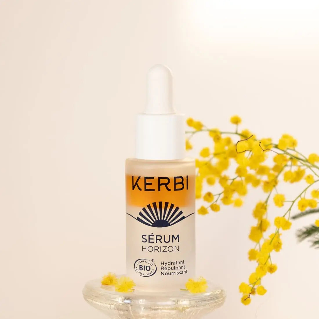 Kerbi After Sun Kasvoseerumi; pullo KERBI Sérum Horizon -tuotetta tippakorkilla lasipinnalla, vieressä pieniä keltaisia kukkia ja taustalla keratiinin ravitsevaa olemusta; pullo lieriömäinen, huurrelasia mattapinnalla, etiketissä pelkistettyä painettua tekstiä ”KERBI Sérum Horizon” selkeällä modernilla fontilla; ei ihmisiä tai käsiä; kuva tasaisesti valaistu ja otettu silmien tasolta.