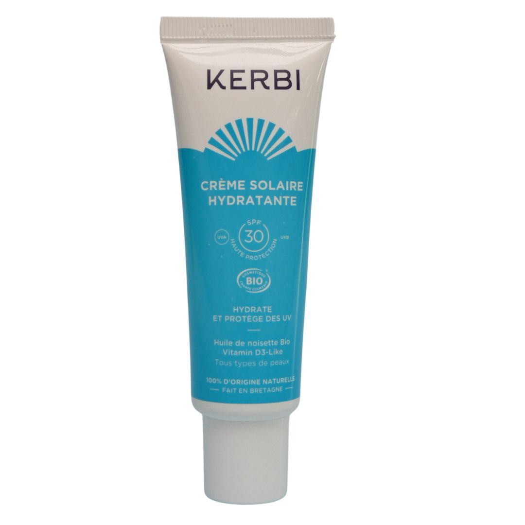 Kerbi Kosteuttava Kasvovoide SPF 30; valkoinen ja sininen tuubi seisoo pystyssä mattapinnalla; tuotteessa teksti ”KERBI Crème Solaire Hydratante SPF 30”, lisäksi mainittu kosteuttava aurinkosuoja, luonnonmukaiset ainesosat ja sopivuus kaikille ihotyypeille; typografia lihavoitua brändinimelle ja tuoteotsikolle; tausta yksivärinen valkoinen, ei ihmisiä tai rekvisiittaa kuvassa.
