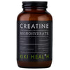 Kiki Health Kreatiini; ruskea sylinterin muotoinen lasipullo mattamustalla kierrekorkilla, tekstinä Creatine Monohydrate KIKI Health -merkiltä, sisältää 120 kasviskapselia; etiketissä valkoista ja vihreää groteskitypografiaa mustaa taustaa vasten; teksti korostaa vegaanista koostumusta, puhtaita ainesosia ja fyysisen suorituskyvyn tukea; tuote kuvattu valkoista taustaa vasten studioasetelmassa, ei ihmisiä tai käsiä.