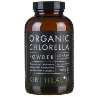 Kiki Health Luomu Chlorella-jauhe; ruskea lasipullo mattapinnalla ja sylinterinmuotoinen, musta kierrekorkki; etiketti on musta valkoisin ja vihrein suuraakkosin, eri kokoisin fontein; tuotenimi, merkki ja paino näkyvissä; pullo, merkitty Organic Chlorella Powder from KIKI Health, 200 g, korostaa 100-prosenttisia raakoja ainesosia, korkeaa rautapitoisuutta, B12-vitamiinia ja muita ravintohyötyjä; tausta valkoinen, ei rekvisiittaa tai käsiä näkyvissä.