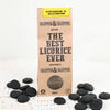 Klepper & Klepper Gluteeniton Lakritsi Honey; ruskea mattapintainen pakkaus lihavoidulla valkoisella tekstillä The Best Licorice Ever lepää tasaisella pinnalla, ympärillään useita kiiltäviä mustia lakritsipaloja; pakkauksessa pienempi teksti kertoo tuotteen olevan gluteeniton, liivatteeton ja hunajan makuinen; ei ihmisiä tai käsiä; neutraali tausta.