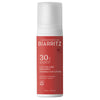 Laboratoires de Biarritz Suncare Invisible Lotion SPF30; valkoinen ja punainen pullo Laboratoires de Biarritz Invisible Sun Lotion SPF 30 -aurinkovoidetta, 100 ml, antioksidanttikompleksilla ja laajakirjoisella UV-suojalla; sylinterin muotoinen mattapinnalla; painetussa etiketissä groteskikirjasinta ranskaksi ja englanniksi; pystyssä oleva pullo kuvattu tasaista neutraalia taustaa vasten ilman ihmisiä tai esineitä.