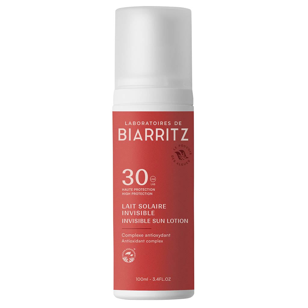 Laboratoires de Biarritz Suncare Invisible Lotion SPF30; valkoinen ja punainen pullo Laboratoires de Biarritz Invisible Sun Lotion SPF 30 -aurinkovoidetta, 100 ml, antioksidanttikompleksilla ja laajakirjoisella UV-suojalla; sylinterin muotoinen mattapinnalla; painetussa etiketissä groteskikirjasinta ranskaksi ja englanniksi; pystyssä oleva pullo kuvattu tasaista neutraalia taustaa vasten ilman ihmisiä tai esineitä.