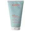 Laboratoires de Biarritz After-Sun Fluid: vaaleansininen tuubi tekstillä "Laboratoires de Biarritz After-Sun Fluid" oranssilla ja valkoisella tekstillä, kosteuttavia ja rauhoittavia ominaisuuksia; tuubi on 150 ml, muovia, mattapinnalla ja valkoisella läppäkorkilla; etuosan teksti korostaa 99,5 % luonnollisia ainesosia; tuote seisoo pystyssä valkoista taustaa vasten studiokuvassa.
