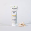 Laboratoires de Biarritz Cleansing Care Kasvokuorinta; tuubi Radiance Scrub -kasvokuorinnalle pystyssä valkoisella alustalla, pieni koralliesine vieressä; tuubi valkoinen mattapintainen turkoosein ja oranssein yksityiskohdin; etiketissä tuotenimi ja brändi groteskifontilla; tausta pysyy tasaisen valkoisena korostaen tätä kuorivaa ihonhoitotuotetta.