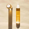 Laboratoires de Biarritz Dry Oil Kuivaöljy; pullo Biarritz Huile Sèche Dry Oil -kuivaöljyä seisoo pystyssä vaalealla, hieman tekstuurisella kovalla pinnalla; pullo kirkasta sylinterin muotoista muovia kiiltopinnalla, sisältää meripihkanväristä nestettä; yläosassa valkoinen pumppuannostelija; etikettikirjasin yksinkertainen ja groteski, tuotenimi mustalla; pullo luo selkeän varjon ja kirkkaan heijastuksen vasemmalle; ei ihmisiä tai käsiä kuvassa.