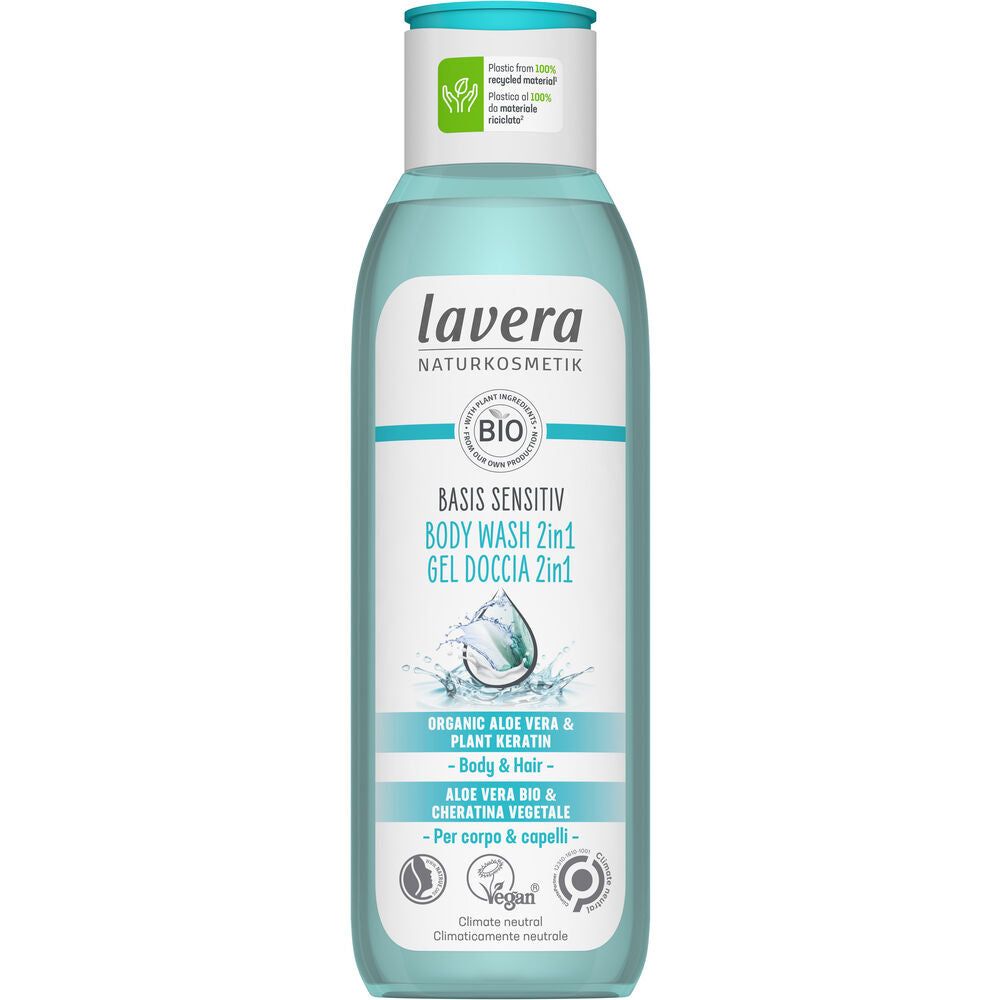 A bottle of Lavera Basis Sensitiv Body Wash 2in1, labeled for body and hair, featuring organic aloe vera and plant keratin. The packaging is mainly light blue and white in color with a matte finish. Vegan and climate-neutral certification icons are present on the front. Text is printed in sans-serif typeface, with product claims in bold. The background is plain white, no people or props are visible.