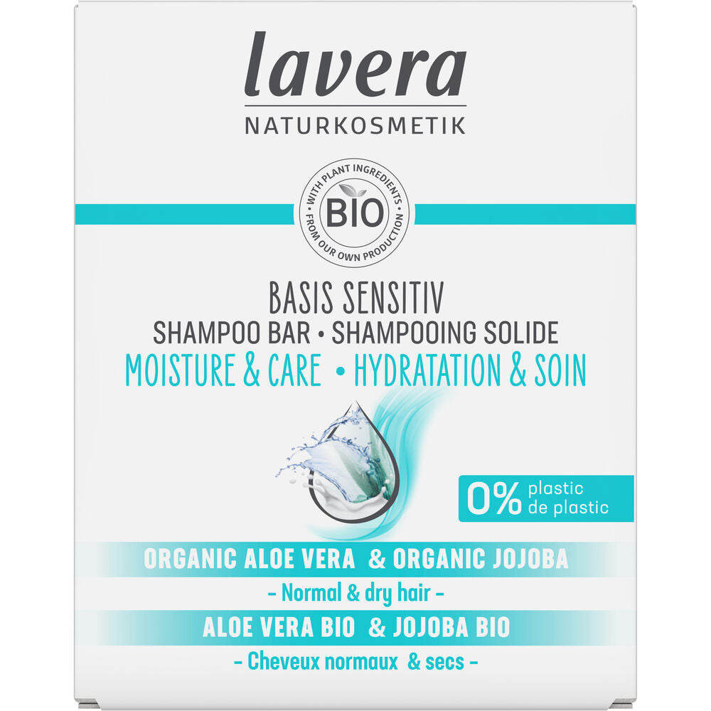 Lavera Basis Sensitiv Moisture & Care Shampoo Bar -pakkaus, jossa sininen vesiroiske; teksti kertoo tuotteen olevan tarkoitettu normaalille ja kuivalle hiukselle, sisältävän luomualoevera- ja jojobaöljyä sekä valmistetun 0 % muovia; suorakaiteen muotoinen pahvipakkaus on vaaleansininen ja valkoinen mattapinnalla; etusivulla groteskikirjasimen typografinen hierarkia; tuotekuva selkeä ilman ihmisiä tai esineitä taustalla.