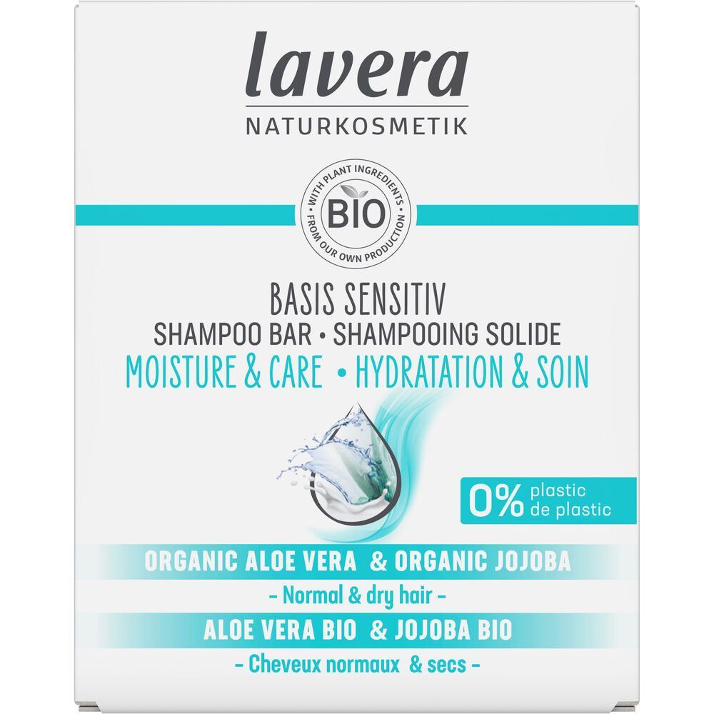 Lavera Basis Sensitiv Moisture & Care Shampoo Bar -pakkaus, jossa sininen vesiroiske; teksti kertoo tuotteen olevan tarkoitettu normaalille ja kuivalle hiukselle, sisältävän luomualoevera- ja jojobaöljyä sekä valmistetun 0 % muovia; suorakaiteen muotoinen pahvipakkaus on vaaleansininen ja valkoinen mattapinnalla; etusivulla groteskikirjasimen typografinen hierarkia; tuotekuva selkeä ilman ihmisiä tai esineitä taustalla.