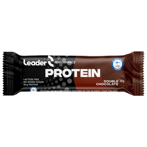 Leader Performance Protein Double Chocolate -patukka ruskeassa ja mustassa kiiltäväpintaisessa kääreessä, jossa lihavoitua valkoista ja kullanvärisiä groteskitekstejä; pakkauksessa lukee 20 g proteiinia, laktoositon ja ei lisättyä sokeria sekä Suomen olympiajoukkueen logo; tuote suorakaiteen muotoinen ja suljettu; tausta neutraali, ei ihmisiä tai muita esineitä näkyvissä.