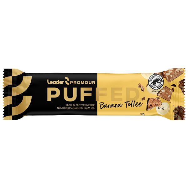 Leader Promour Puffed Banana Toffee -patukan keltainen ja musta kääre, jossa kuvia patukasta ja sen raaka-aineista; mattapintainen pakkaus serifi- ja groteskikirjasimin; etusivulla tuotenimi, maku sekä kuvakkeet tai teksti runsaasta proteiinista, kuidusta, ilman lisättyä sokeria ja ilman palmuöljyä; patukan muoto suorakaiteen mallinen; neutraali studiotausta ilman käsiä tai ihmisiä.