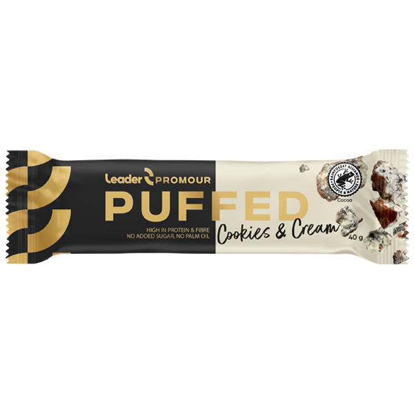 Leader Promour Puffed Cookies Cream -proteiinipatukka mustassa, kullanvärisessä ja valkoisessa kiiltäväpintaisessa pakkauksessa, jossa keksin ja kermatäytteen palasia sekä tekstiä runsaasta proteiinista ja ilman lisättyä sokeria; pakkaus on suorakaiteen muotoinen; typografia lihavoitua groteskikirjasinta valkoisella ja kullanvärisellä; tuote makaa tasaisella alustalla ilman taustaelementtejä tai ihmisiä.