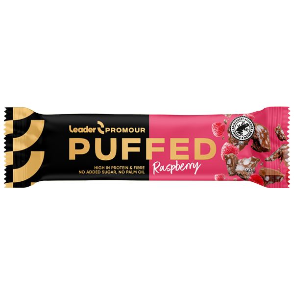 Käärepakattu PUFFED Raspberry -proteiinipatukka Leader Promourilta, pakkaus musta ja pinkki pähkinä- ja vadelmakuvin. Pakkauksen pinta on kiiltävä, suorakulmainen muoto suljetuin päin. Pääteksti on valkoista pääteviivatonta ja lihavoitua fonttia, pienempi lisäteksti pienemmällä koolla. Tausta on pelkistetty valkoinen studiotausta, ei ihmisiä tai käsiä. Teksti korostaa korkeaa proteiinipitoisuutta, ettei tuotteessa ole lisättyä sokeria eikä palmuöljyä.