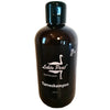 Tumma, lieriömäinen pullo, jossa lukee Lehto Peat Turveshampoo 250 ml, mattapinnalla ja valkoinen joutsenlogo sekä teksti feel the peat etusivulla selkeällä groteskikirjasimella; pakkaus näyttää olevan muovia tasaisella korkilla; tuote keskitettynä valkoiselle taustalle, kuvattuna ilman ihmisiä tai muita esineitä.