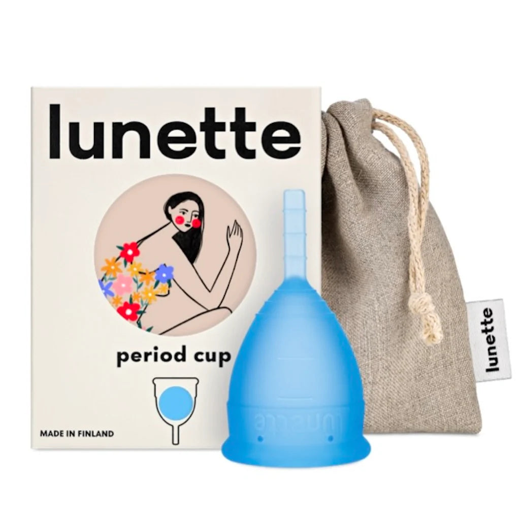 Lunette Kuukautiskuppi Sininen, sininen kuppi Lunette-rasian ja harmaan vetonyörillisen pussin edessä, rasiassa kukkakuvitus