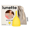 Lunette Kuukuppi Keltainen, keltainen silikonikuppi Lunette-rasian ja harmaan vetonyörillisen pussin edessä