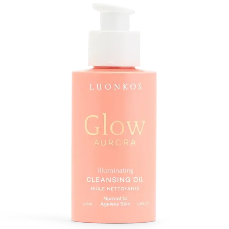 Luonkos Glow Aurora Cleansing Oil; vaaleanpunainen pullo Luonkos Glow Aurora Illuminating Cleansing Oil -puhdistusöljyä valkoisella muovisella pumpulla; pullo sileällä mattapinnalla ja lieriömäisellä muodolla; kultaista ja valkoista etikettitekstiä yksinkertaisin groteskifontein, sisältää tuotenimen ja käyttöohjeet normaalille tai ikääntymättömälle iholle; tuote yksin yhtenäistä taustaa vasten.