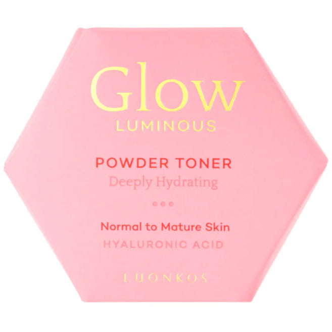 Luonkos Glow Luminous Powder Toner; vaaleanpunainen kuusikulmainen kosmetiikkapakkaus tekstillä ”Glow Luminous Powder Toner”, syvästi kosteuttava hyaluronihappo normaalille ja kypsälle iholle, valmistaja LUONKOS; pinta mattapintainen pahvia; etikettiteksti painettu tikkukirjasimella vaihtelevin painoin; pakkaus tasaisella valkoisella taustalla ilman näkyviä ihmisiä tai rekvisiittaa, kuvattu ylhäältä.