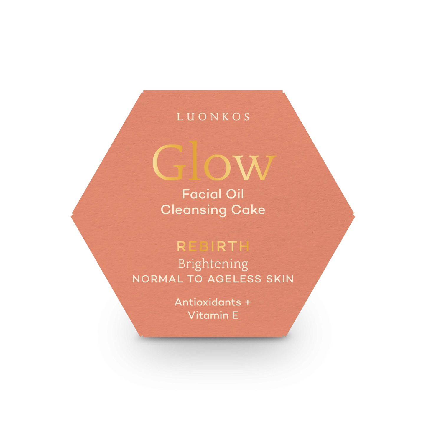 Luonkos Glow & Shine Skincare Set; kuusikulmainen persikanvärinen rasia tekstillä ”LUONKOS Glow Facial Oil Cleansing Cake: Rebirth Brightening, Normal to Ageless Skin”, sisältää antioksidantteja ja E-vitamiinia, valkoisella taustalla; mattapintainen paperipakkaus mustalla tikkukirjasimella ja kultaisella antiikvatypografialla etusivulla; ei ihmisiä tai käsiä kuvassa; rasia keskitettynä tasaiselle valkoiselle taustalle, kuvattu ylhäältä hieman viistosti.