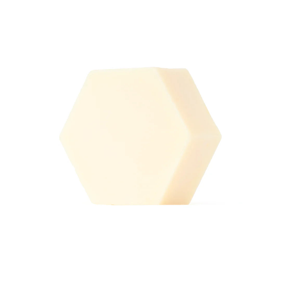 Luonkos Hydrate Essence Hand & Body Soap; yhtenäinen, kermanvärinen kuusikulmainen kappale keskitettynä puhtaalle valkoiselle taustalle, esitellen geometrista tyylikkyyttä; kappaleessa ei näkyvää tekstiä tai merkintöjä, pinta sileä ja mattapintainen, ei pakkausta ympärillä; kuva yksinkertainen studiotuotekuva tasaisessa valaistuksessa ilman ihmisiä tai käsiä.