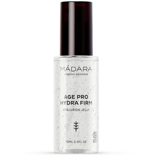 Madara AGE PRO Hydra Firm Hyaluron Jelly; kirkas pullo Mádara Age Pro Hydra Firm Hyaluron Jelly -tuotetta tummalla pumppukorkilla, sisältää 75 ml; muoto on sylinterinmuotoinen sileine sivuineen ja kiiltäväpintainen; etiketissä yksinkertaista mustaa groteskitekstiä ja pieni lehtimerkki; näkyvissä olevat sanat sisältävät tuote- ja merkin nimen sekä ”hyaluronic acid”; ei ihmisiä tai käsiä näkyvissä; valkoinen tausta, lähikuva.