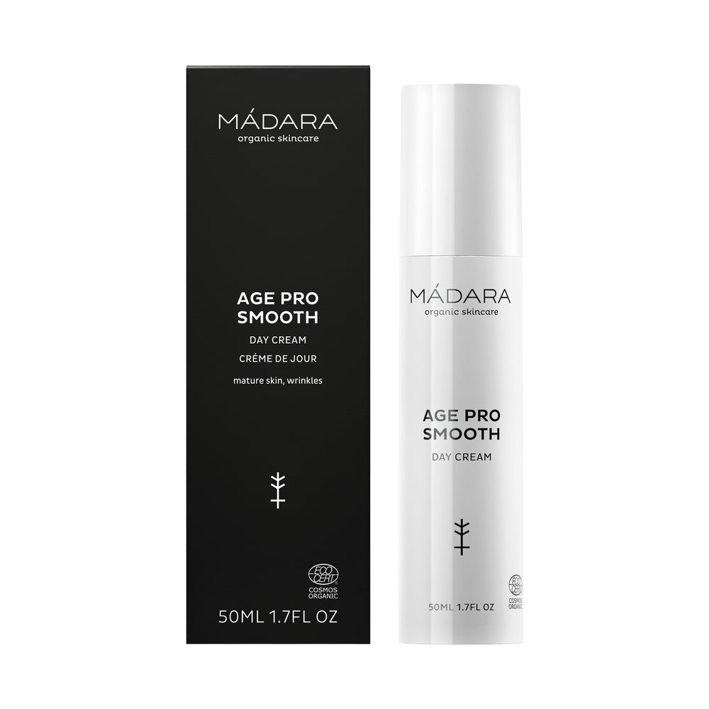 Madara AGE PRO Smooth Day Cream; valkoinen pullo ja musta laatikko MÁDARA Age Pro Smooth Day Cream -tuotetta kypsälle iholle; molemmat pakkauspinnat mattapintaisia, minimalistista groteskityypografiaa valkoisella ja hopealla; pullo on sylinterinmuotoinen pumppuannostelijalla, laatikko suorakulmainen; molemmissa pieni kasvikuvake, merkintä ”50 ml (1.7 fl oz)” ja tuotetiedot selkeinä tekstilohkoina; ei ihmisiä tai muita elementtejä näkyvissä; lähikuva studiotyyliin.