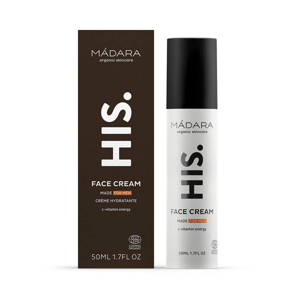Madara HIS Face Cream; kasvovoide miehille, 50 ml:n pullo laatikkonsa vieressä; pullo on sylinterinmuotoinen mustalla mattapinnalla ja valkoisella groteskitekstillä; laatikko on suorakulmainen samankaltaisin brändäyksin ja kirjasimin; etiketissä mainitaan C-vitamiinienergia ja luomuainesosat ihon elvyttämiseksi; yksivärinen tausta, studiovalaistus, ei ihmisiä näkyvissä.