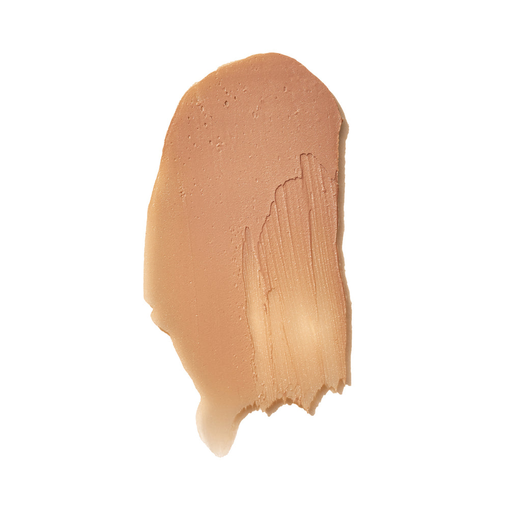 Mádara Mineral SPF50 Sunscreen Stick; beigen värinen meikkivoidenäyte, tasaisesti levitetty näkyvin siveltimen jälkin valkoiselle taustalle; koostumus on keskipaksu ja tuote peittävä, siveltimen suunnat erottuvat selkeästi; ei pakkausta, etikettejä tai tekstiä näkyvissä; suuritarkkuuksinen lähikuva näyttää meikin kermaisen koostumuksen ja hienon kiillon yksiväristä taustaa vasten.
