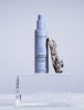 Madara Retinol Alternative Plant-Powered Day Cream; sylinterinmuotoinen pullo, merkitty ”Mádara Retinol Alternative Day Cream”, seisoo pystyssä läpinäkyvällä, kiinteällä jäälohkolla; pullon vieressä tekstuuripintainen ruskea kaarnan pala; pullo on mattapastellisella pinnalla selkeällä mustalla groteskitekstillä; tausta on tasaisen kirkas ja siisti, luoden kontrastin tuotteeseen ja rekvisiittaan nähden; ei ihmisiä tai toimintaa näkyvissä.