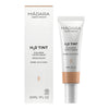 Madara H2O Tinted Hyaluron Serum; valkoinen rasia ja yhteensopiva tuubi tekstillä ”Mádara H₂O Tint Hyaluron Tinted Serum, Shade: Sun Flower, 30 ml”; molemmissa mattapinta ja suorakaiteen muotoinen tuubi valkoisella korkilla; teksti yksinkertaisella mustalla groteskilla ja pieni lehtikuvake kummassakin pakkauksessa; tausta tasainen valkoinen, ei ihmisiä tai käsiä.