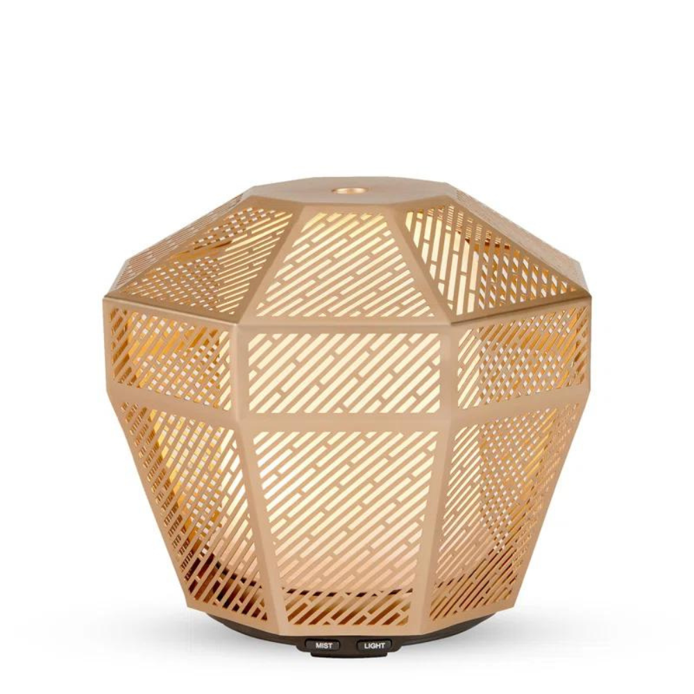Made by Zen Luminarie Gold Diffuuseri; geometrinen, kullanvärinen aromidiffuusori, jossa yksityiskohtaisia leikkauskuvioita, sisältä valaistu lämpimän tunnelmallisen hehkun luomiseksi; pohjassa höyry- ja valopainikkeet; pinta on metallinen ja kiiltävä; ei näkyvää pakkausta tai merkkiä; kuvassa vain tuote yksiväristä taustaa vasten, ei ihmisiä tai muita esineitä.