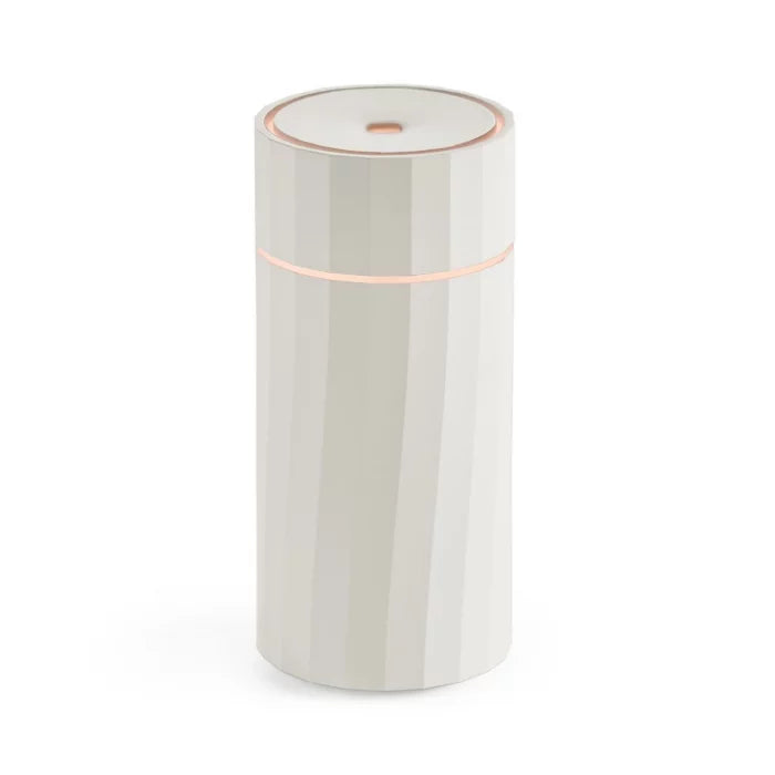 Made by Zen Nomad USB Diffuuseri; valkoinen, sylinterinmuotoinen älylaite, jossa hienovarainen ura yläosassa ja ohut vaakasuuntainen valo lähellä huippua, seisoo pystyssä yksivärisellä taustalla; muovirunko mattapinnalla, ei näkyviä logoja tai tekstiä, sileä pinta; ei pakkausta näkyvissä; tasaisesti valaistu, ilman varjoja tai heijastuksia, tuote keskitetty ja yksin kuvassa, kuvattu suoraan edestä pöytäkorkeudelta; ei ihmisiä tai käsiä näkyvissä.