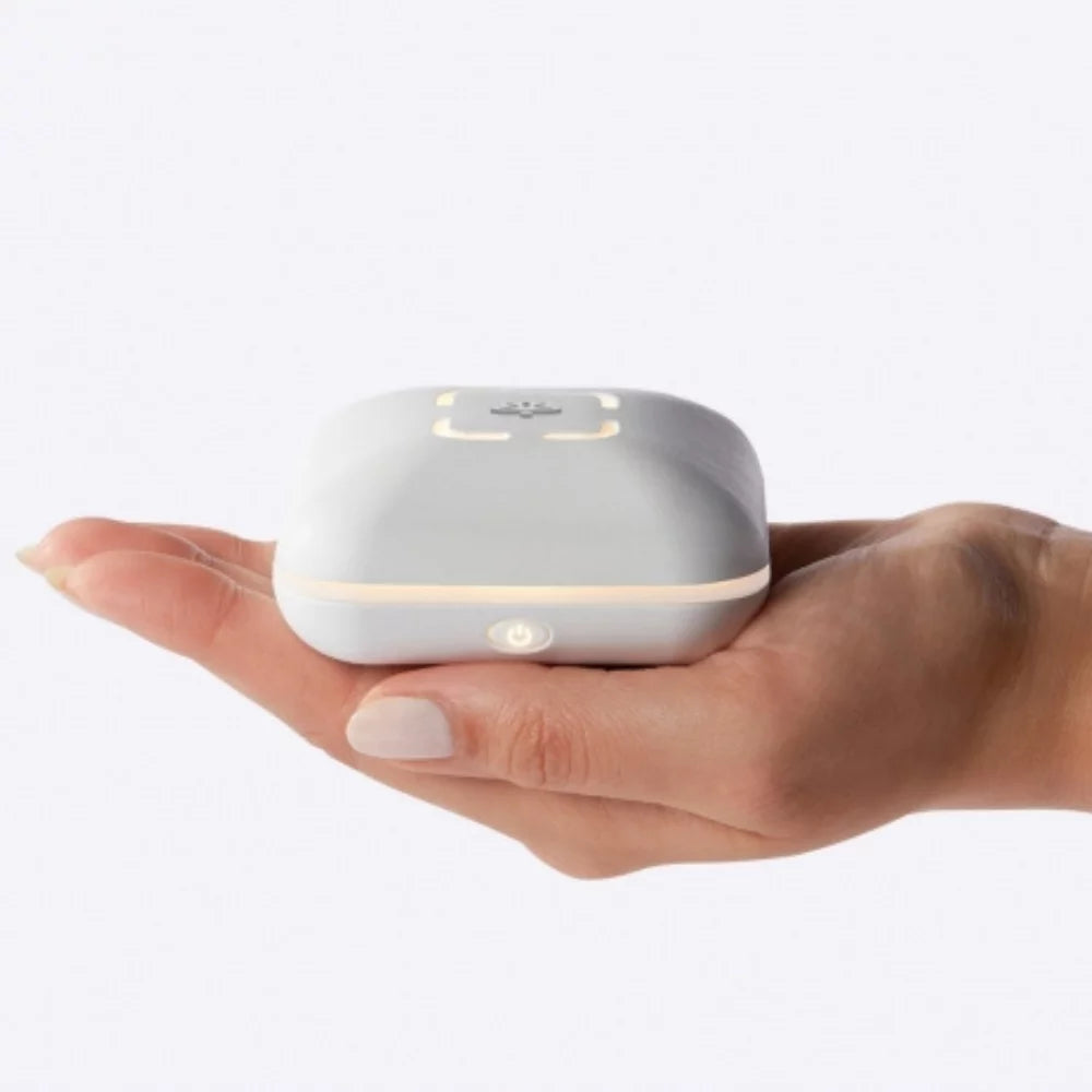 Made by Zen Peri USB Diffuuseri; käsi pitelee pientä valkoista suorakulmaista älylaitetta pyöristetyin reunoin ja pehmeästi hehkuvin valoin pinnallaan, vaalealla taustalla; laite on sileän mattapintainen ilman näkyviä painikkeita tai tekstiä; kuvassa on vain yksi ihmiskäsi ylhäältä kuvattuna tuotetta pitelemässä, ei muita esineitä tai pakkausta näkyvissä.