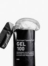 Maurten Gel 100 (12-pack), musta urheilugeelipussi merkitty "Hydrogel Sports Fuel GEL 100", geeliä valumassa ulos; pakkaus mustaa mattapintaista, joustava suorakulmainen muoto; ainesosat ja ravintosisältötiedot painettu selkeästi pienellä fontilla takaosaan; pääetiketti käyttää groteskityppografiaa; tausta valkoinen, lähikuva tuotteesta, ei ihmisiä eikä käsiä näkyvissä.